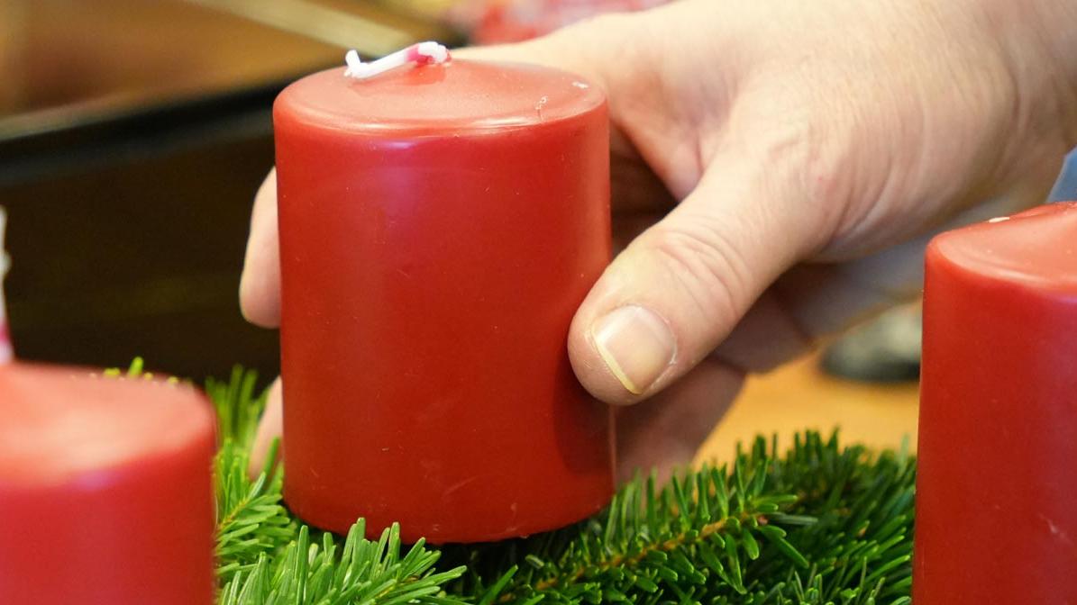 Hand richtet Adventskranz zurecht.