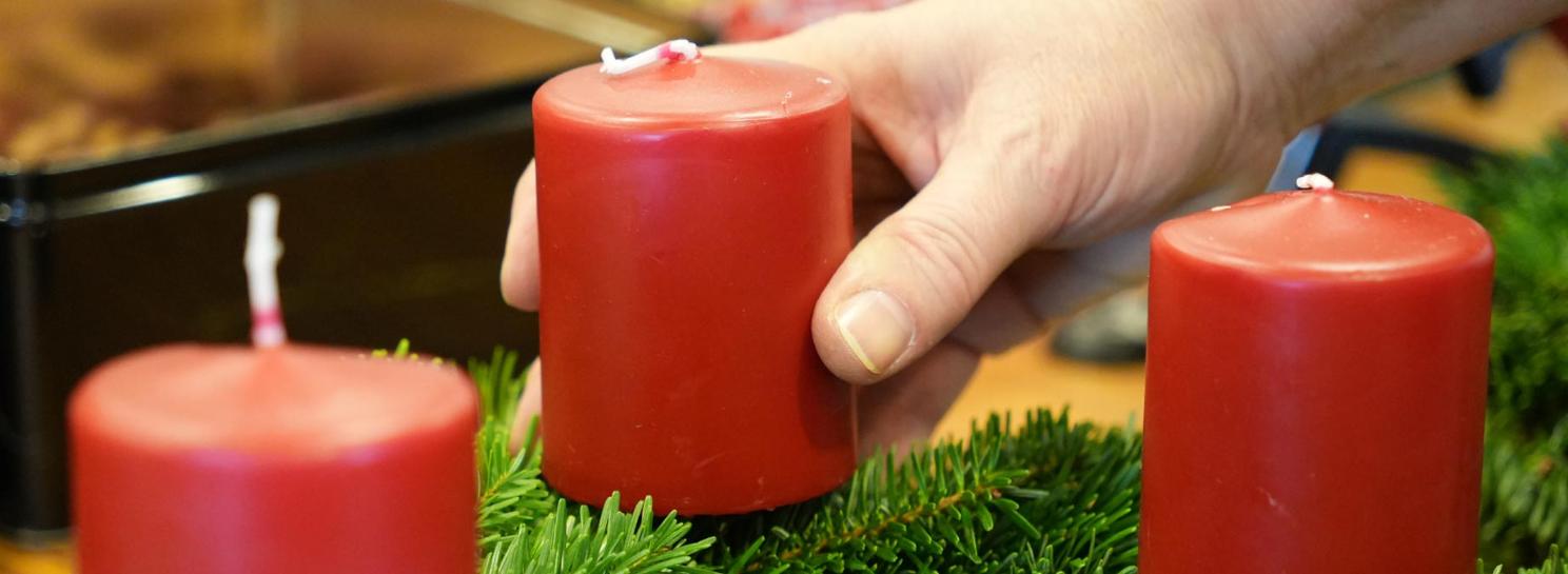 Hand richtet Adventskranz zurecht.