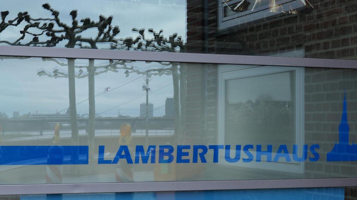 Schriftzug Lambertushaus mit Spiegelung der Rheinbrücke und der Rheinpromenade