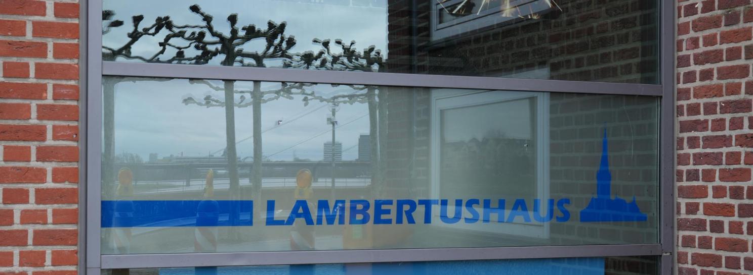 Schriftzug Lambertushaus mit Spiegelung der Rheinbrücke und der Rheinpromenade