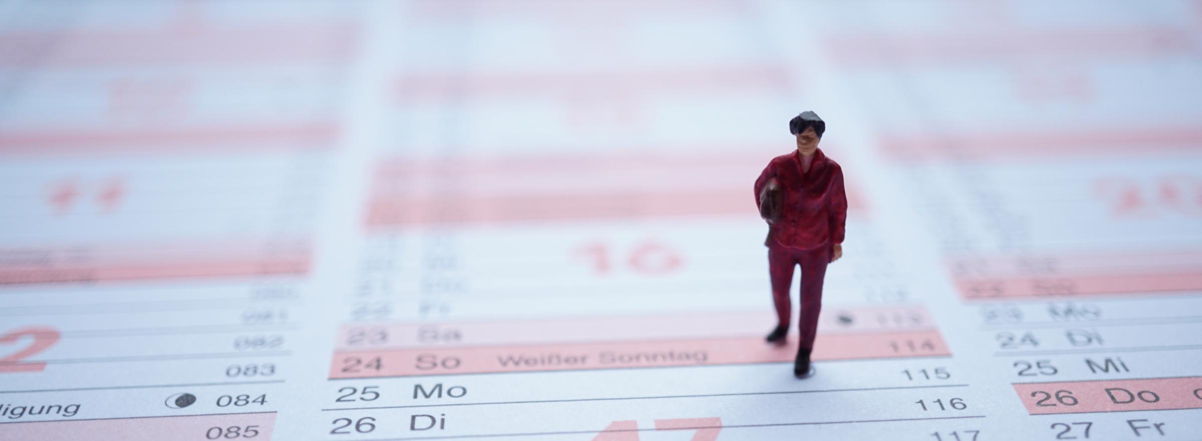 Miniaturfigur Frau mit Tasche auf Jahreskalender stehend