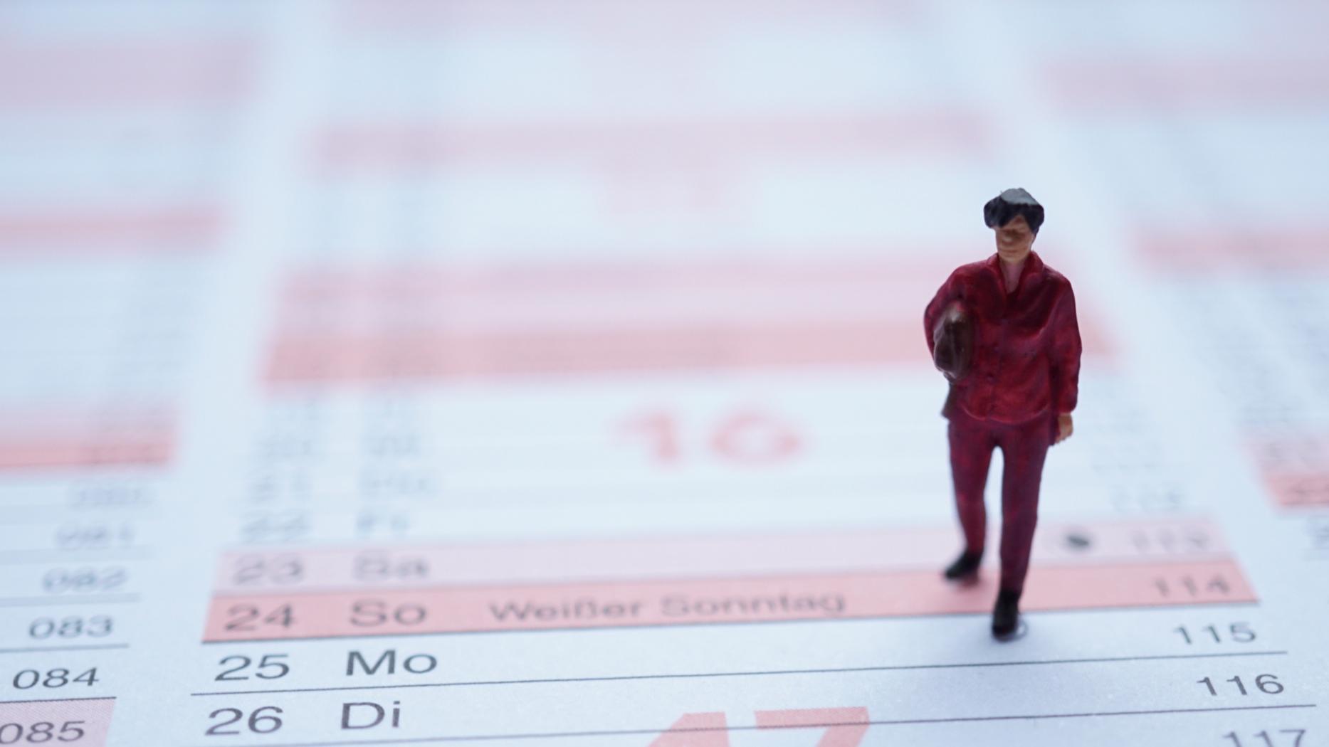 Miniaturfigur Frau mit Tasche auf Jahreskalender stehend