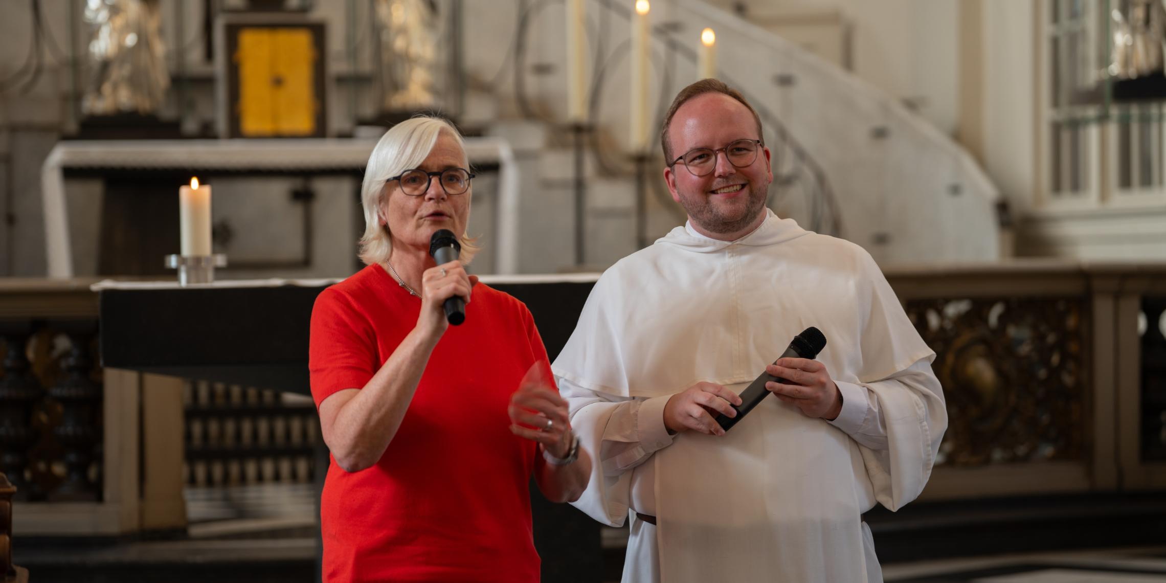 Eine Frau und ein Dominikaner sprechen in der Kirche St. Andreas